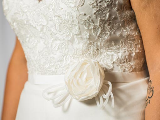 Dettaglio cintura in raso con fiore nel punto vita. Idee per un abito da sposa taglie forti. Collezione Inclusive.